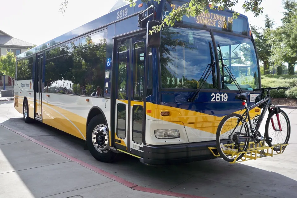 White and blue Sacramento regional transit bus with one bike on front bike rack.